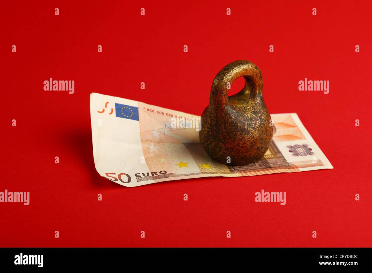 Euro banknote under weight on red background Stock Photo Alamy