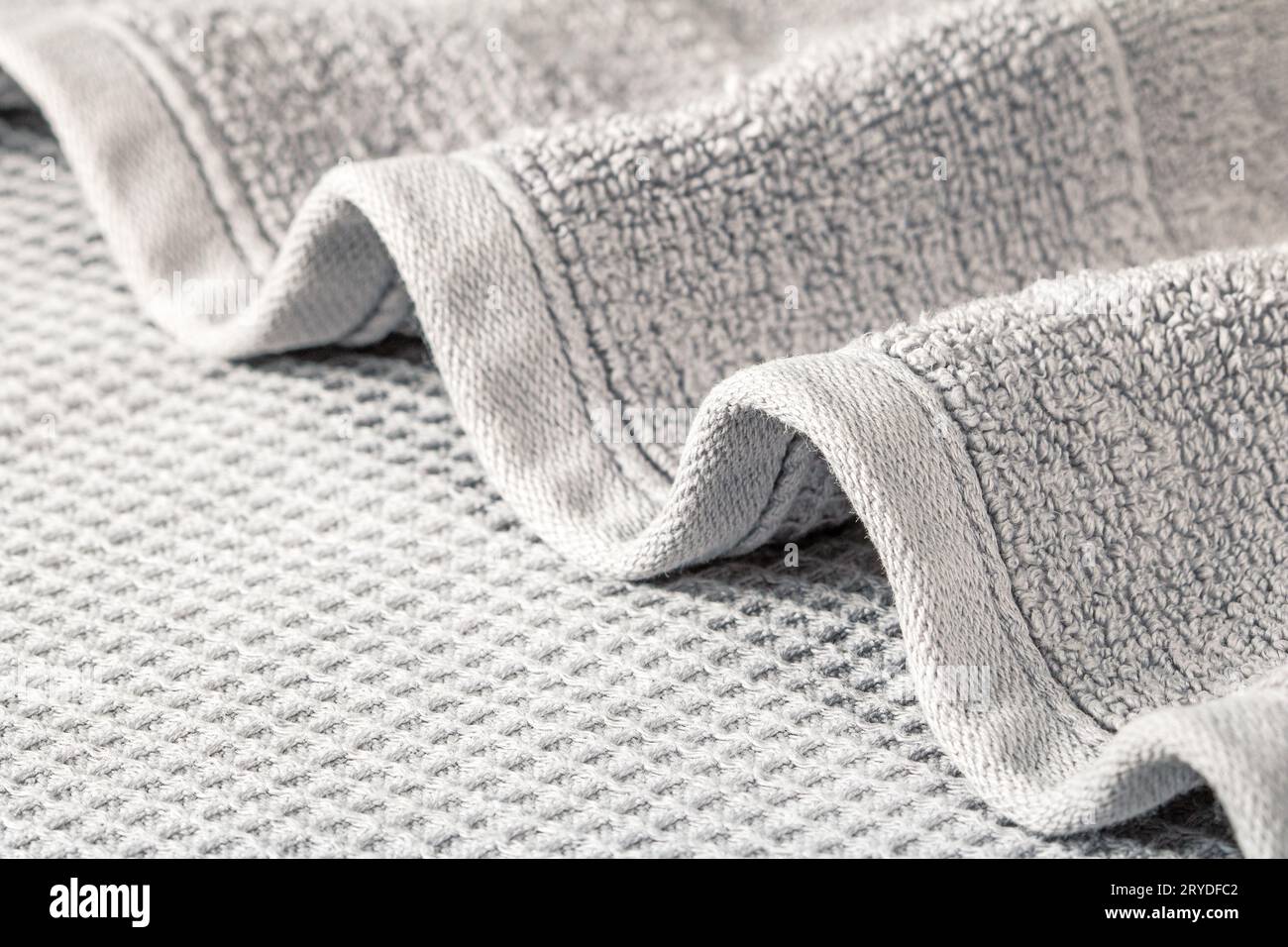 Soft terry towel folded in waves on a gray background close-up. Stock Photo