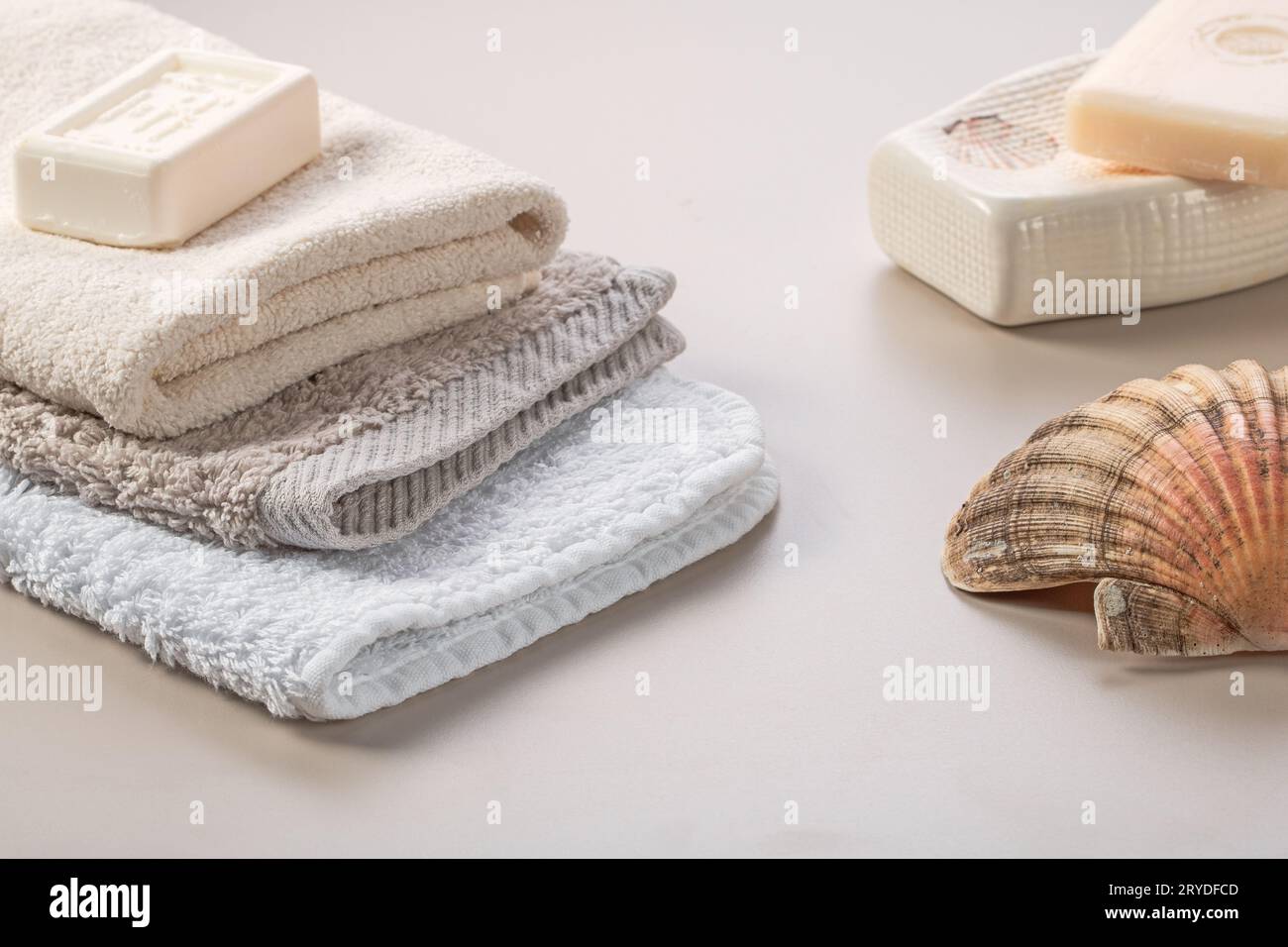 Bathroom accessories. Stack of towels, soap and shell on the dressing table. Stock Photo