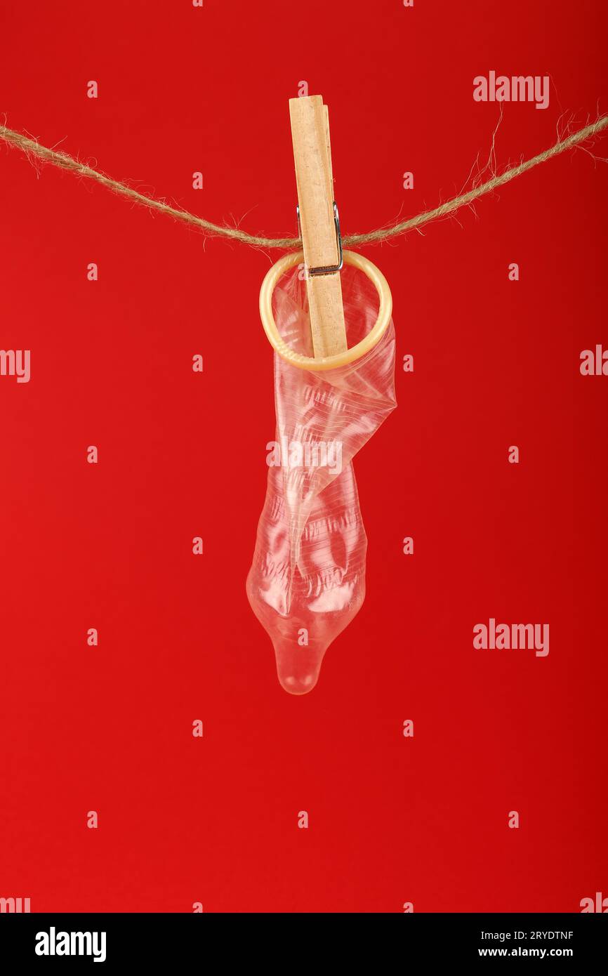 One condom hanging on washing line over red Stock Photo