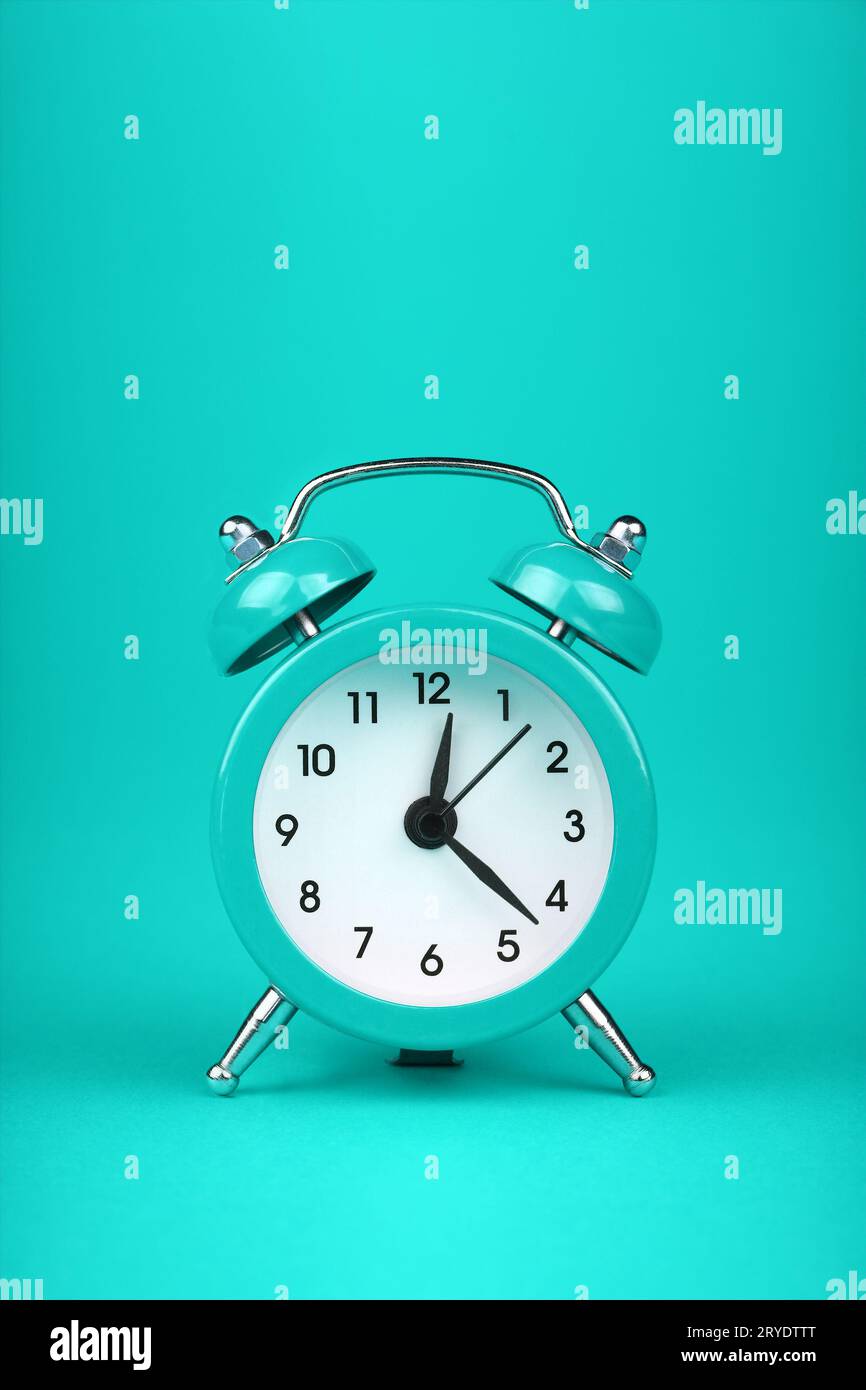 Close up one teal blue alarm clock over turquoise Stock Photo
