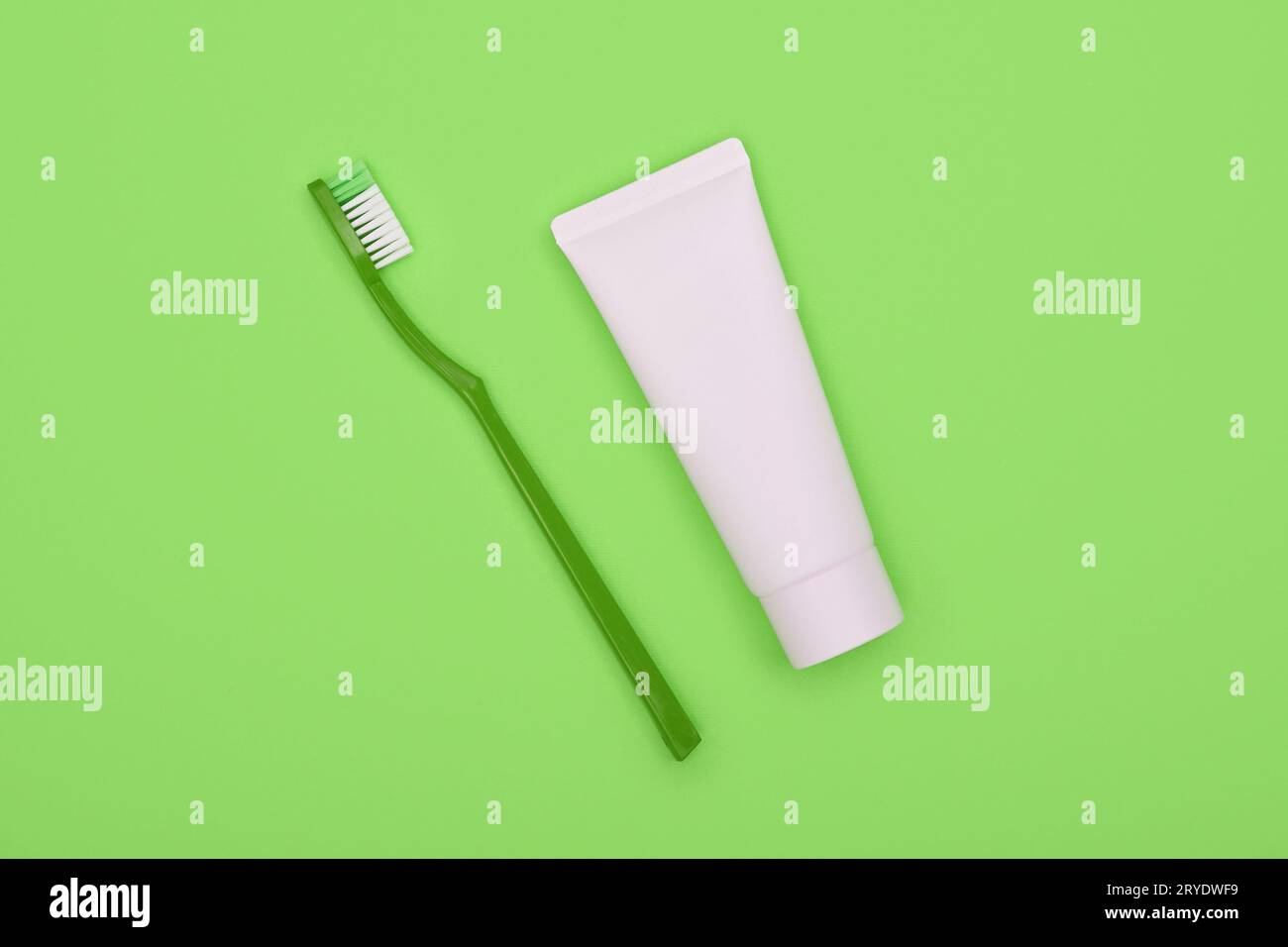White toothpaste and plastic toothbrush on green Stock Photo