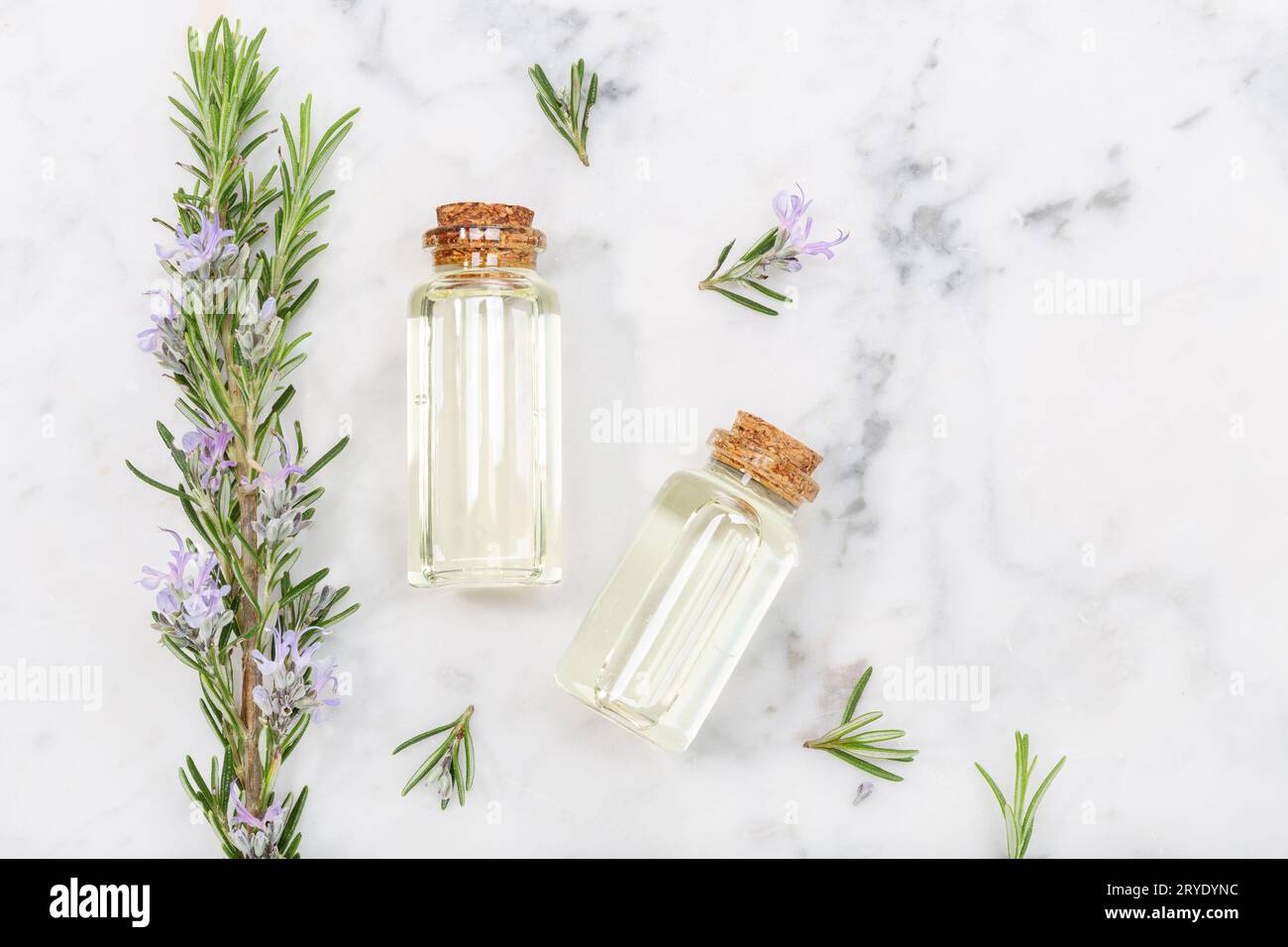 Rosemary essential oil in glass bottle and twigs on marble table Stock Photo