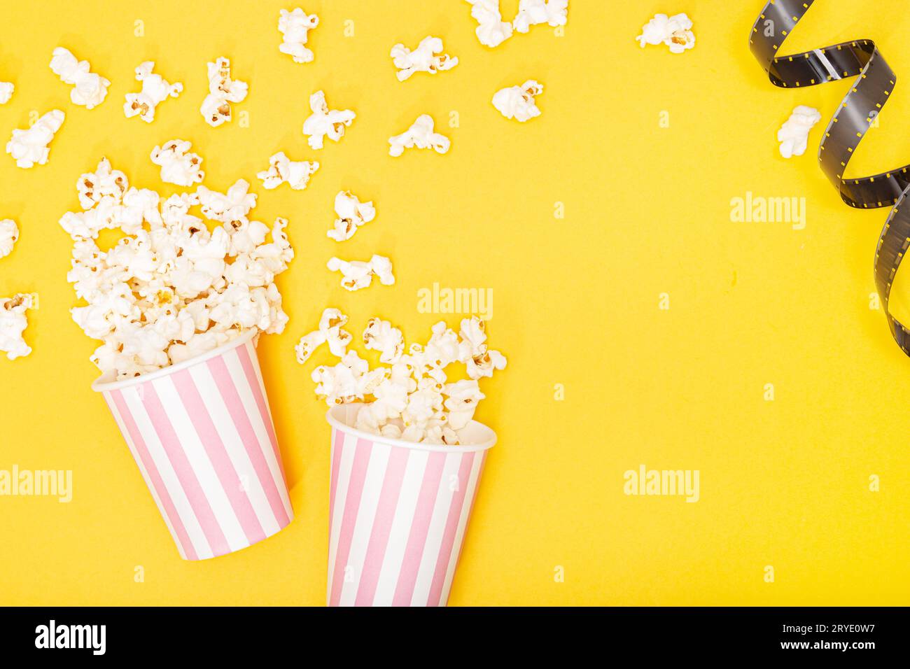 Popcorn bucket and film strip on yellow background Stock Photo
