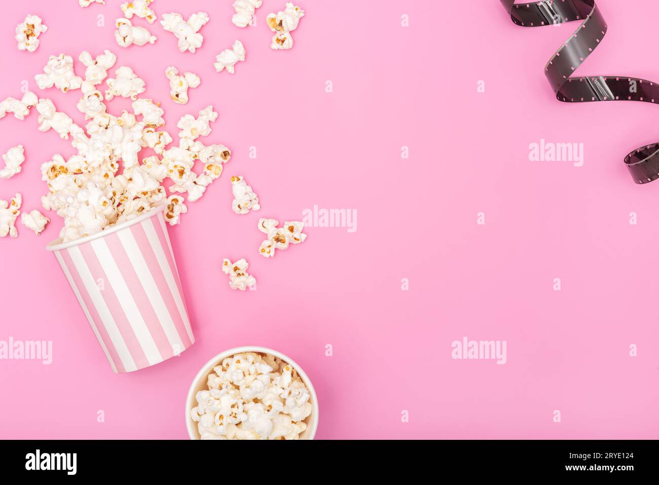Popcorn bucket and film strip on pink background Stock Photo
