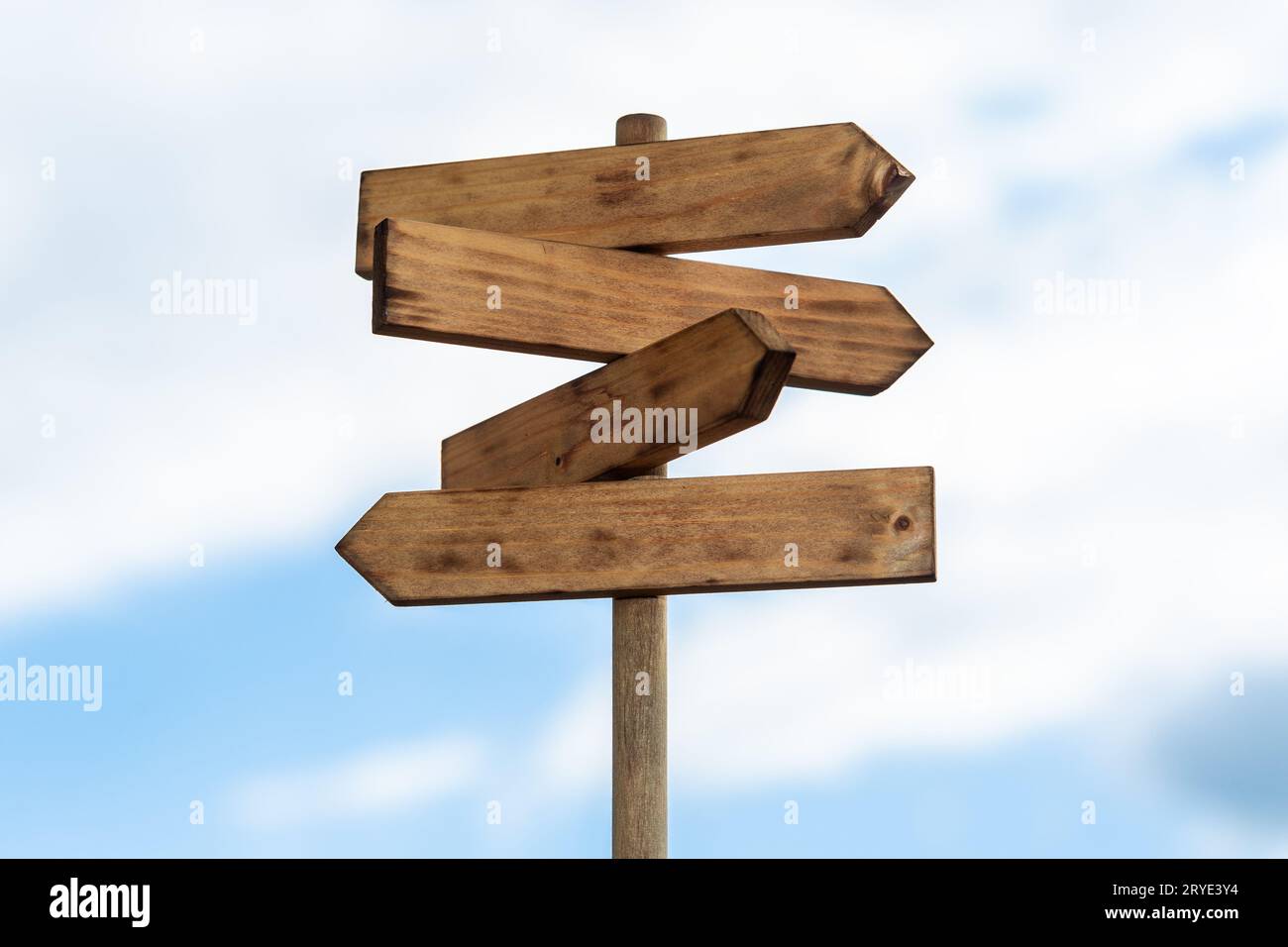 Wooden sign post isolated on blue sky with white clouds Stock Photo