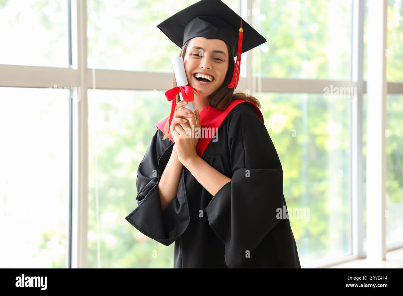 Female graduate student with diploma near window in room Stock Photo ...