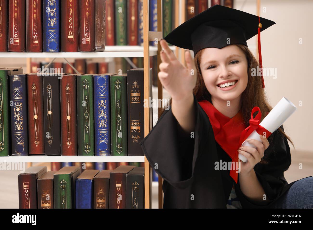 Female graduate student with diploma in library Stock Photo - Alamy