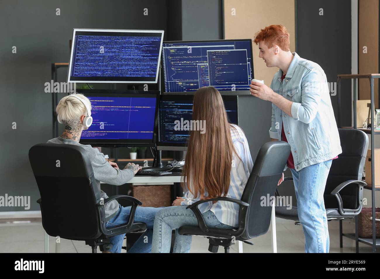 Young programmers with coffee working in office, back view Stock Photo
