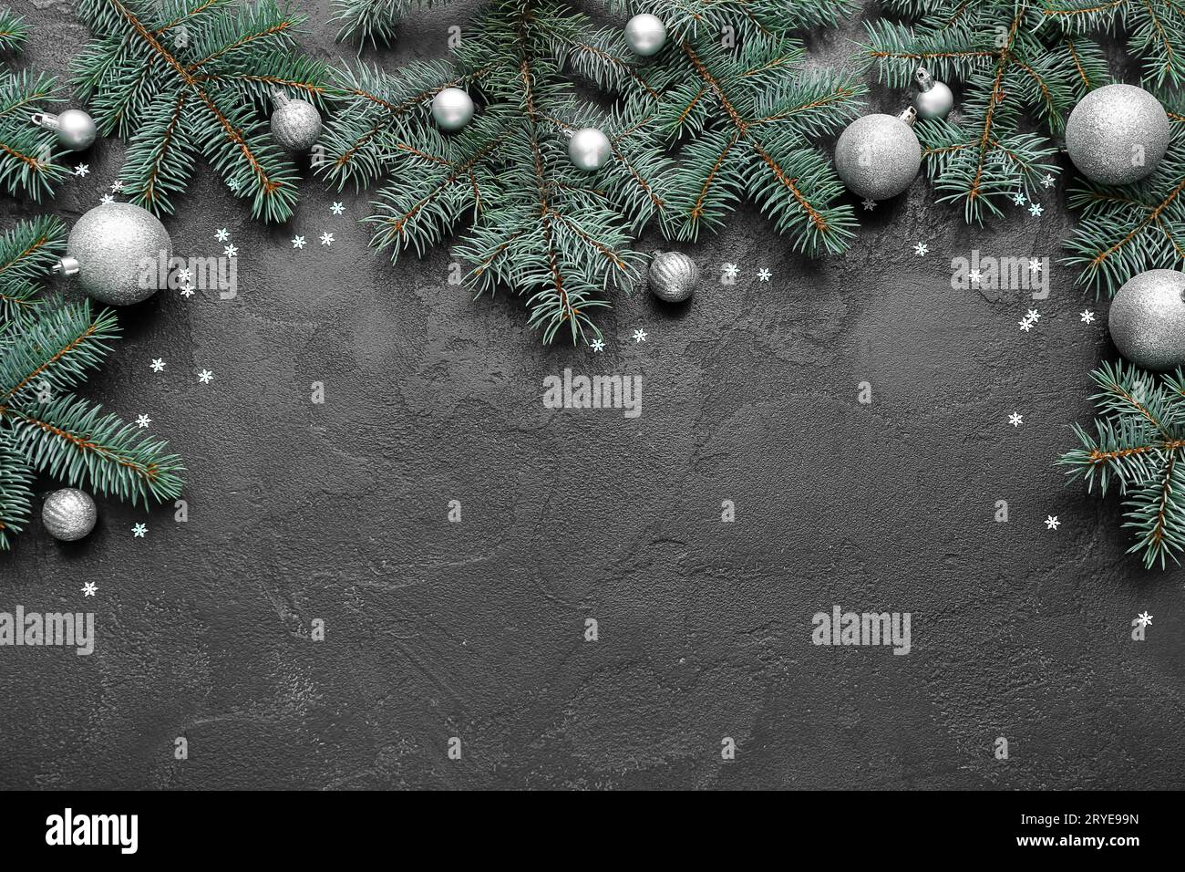 Christmas tree branches with balls and confetti on black background ...