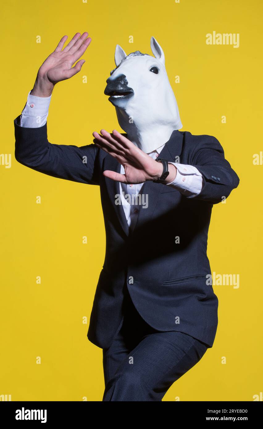 A man in a suit and a horse mask on a yellow background. Conceptual