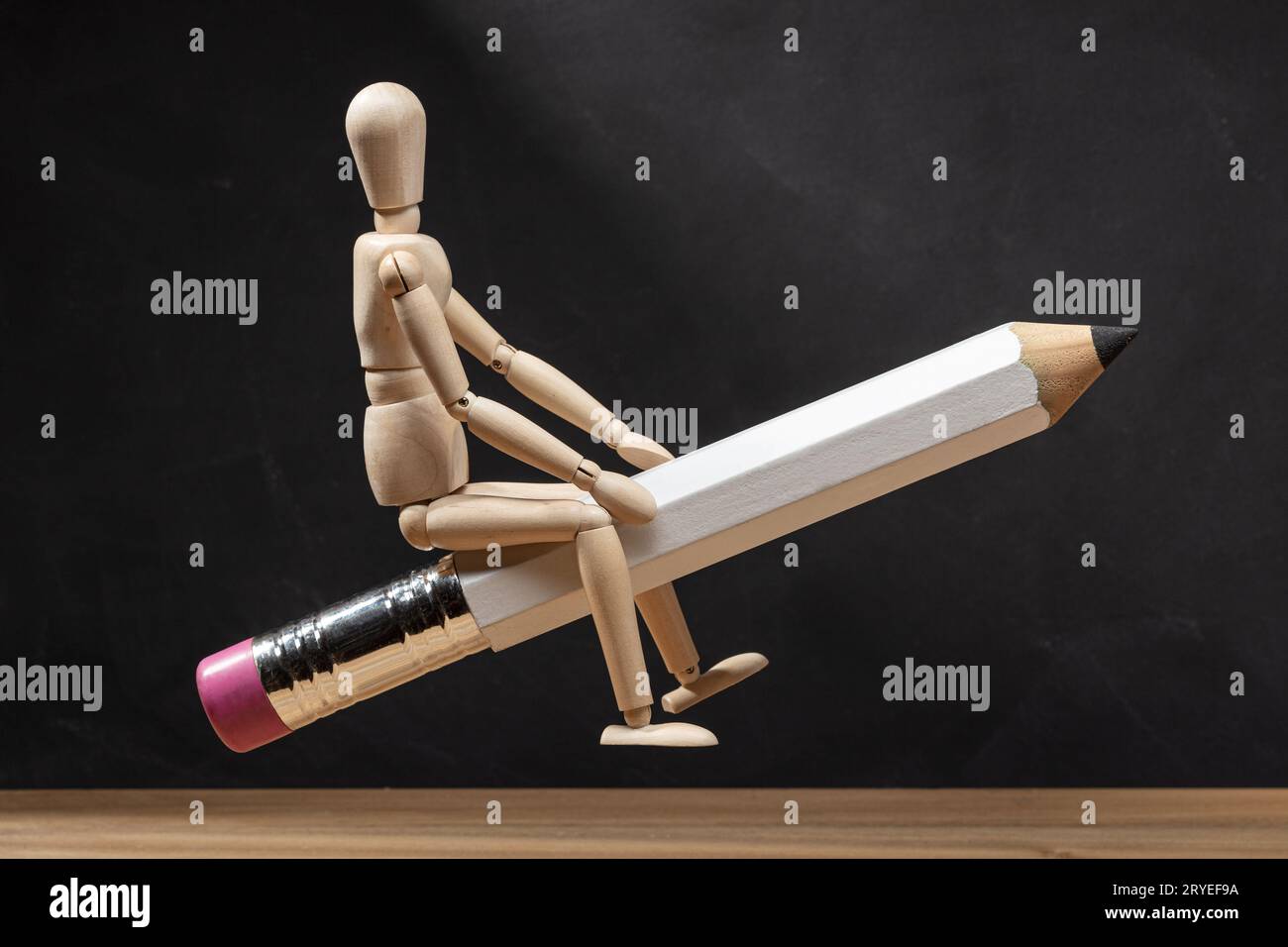 Wooden mannequin riding a pencil like a rocket Stock Photo