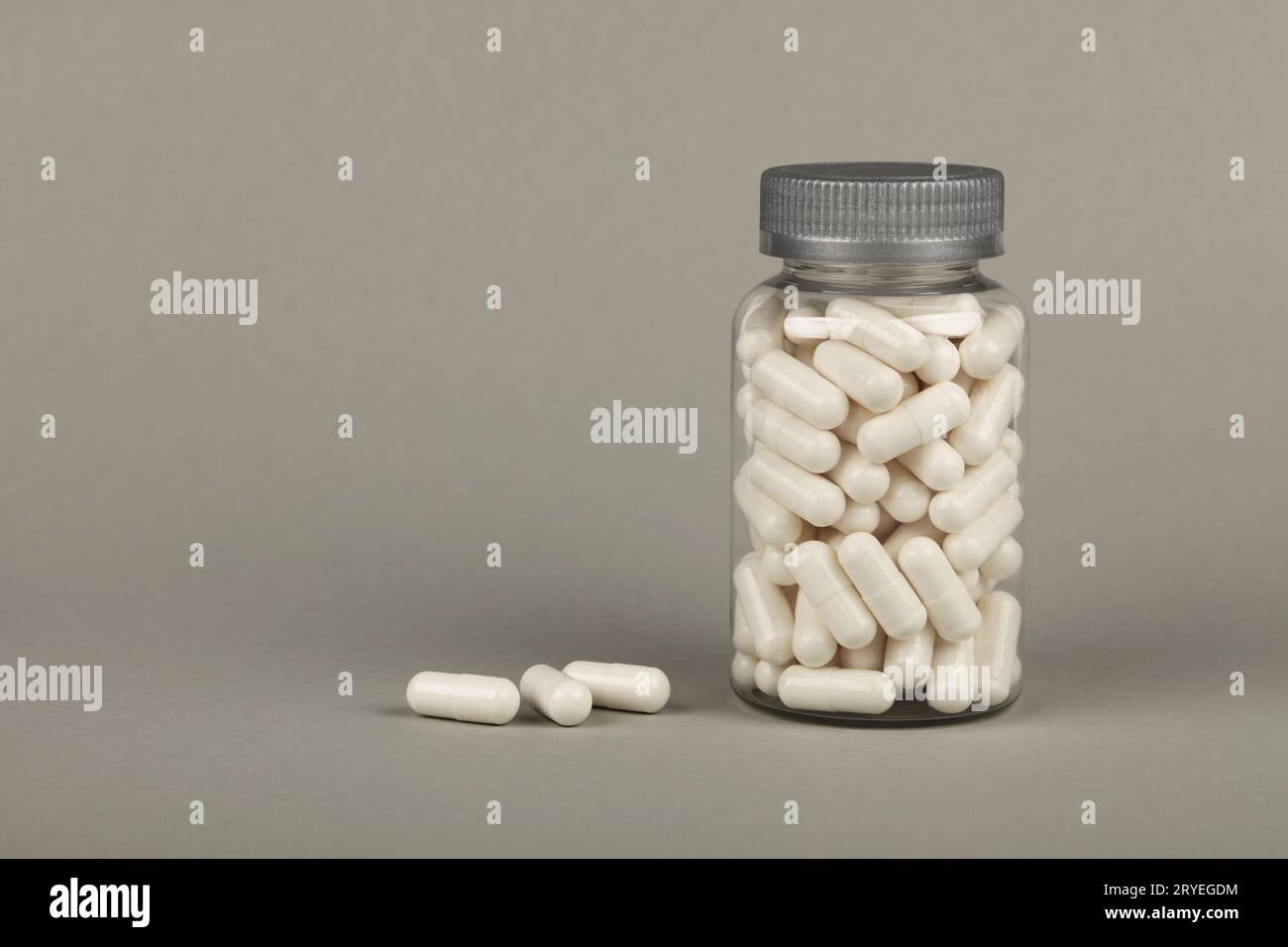 Bottle of white gel cap pills over grey Stock Photo