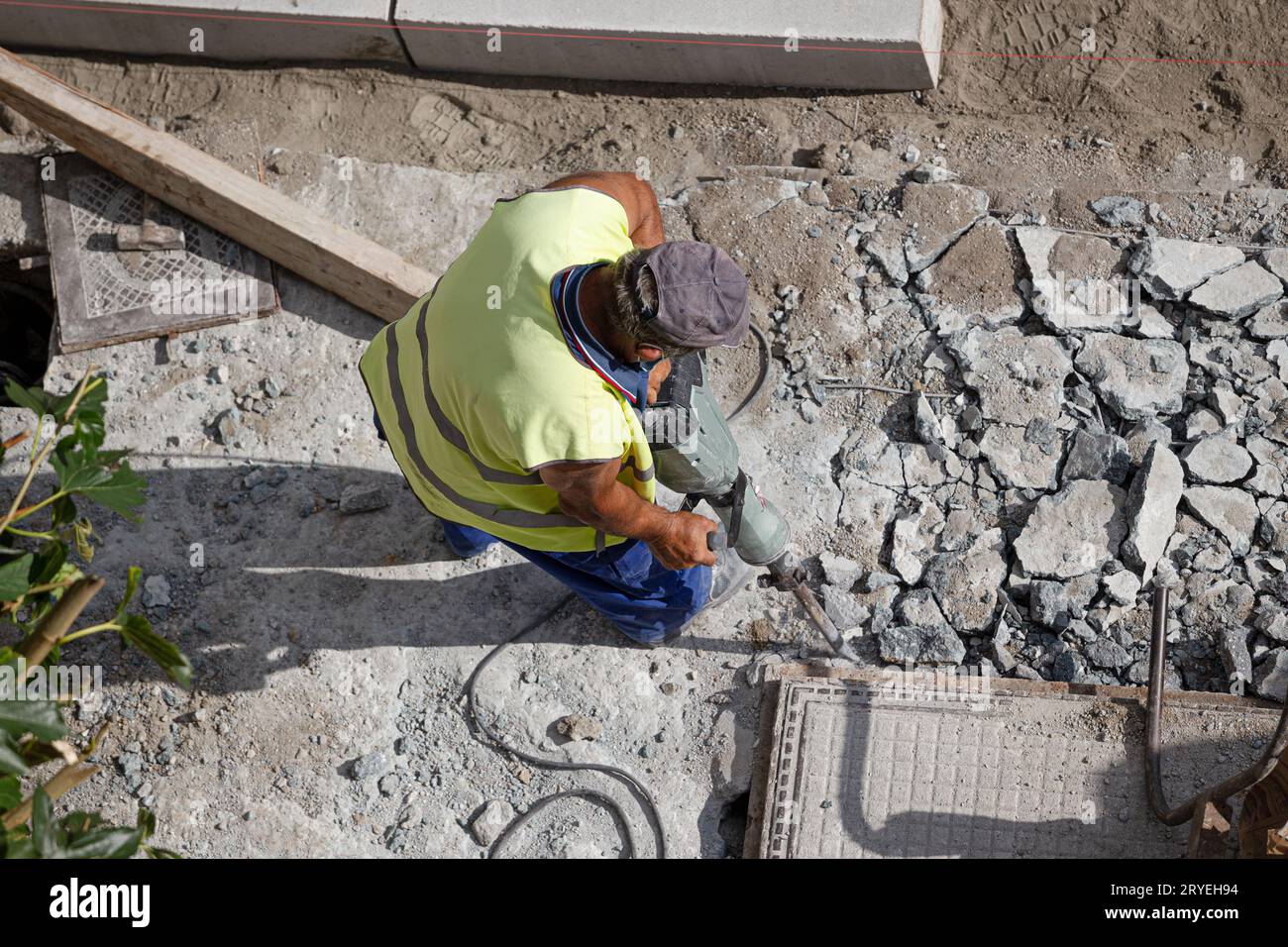 Construction worker with jackhammer drilling concrete on sidewalk Stock Photo
