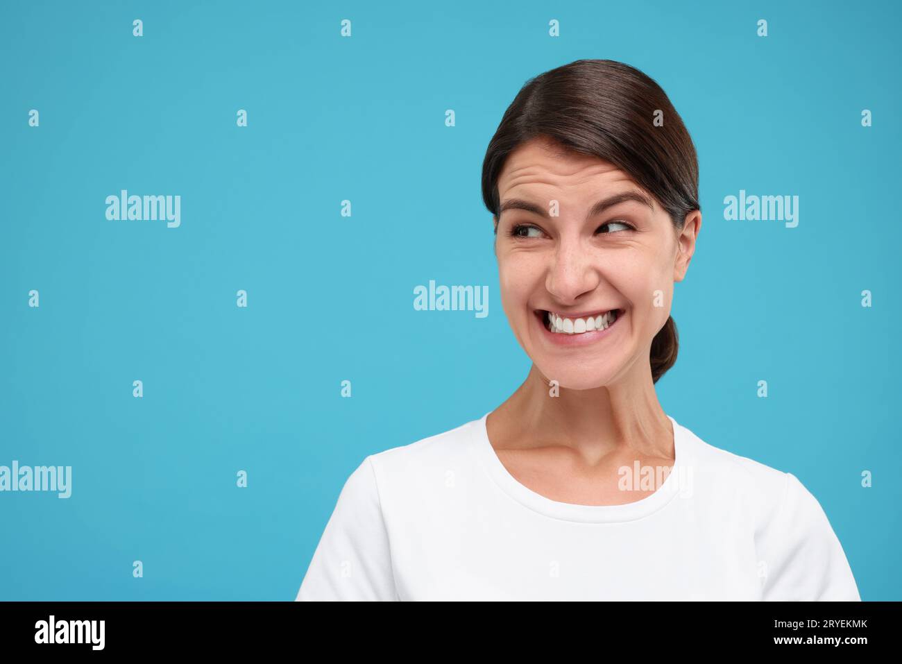 Portrait of embarrassed young woman on light blue background, space for ...