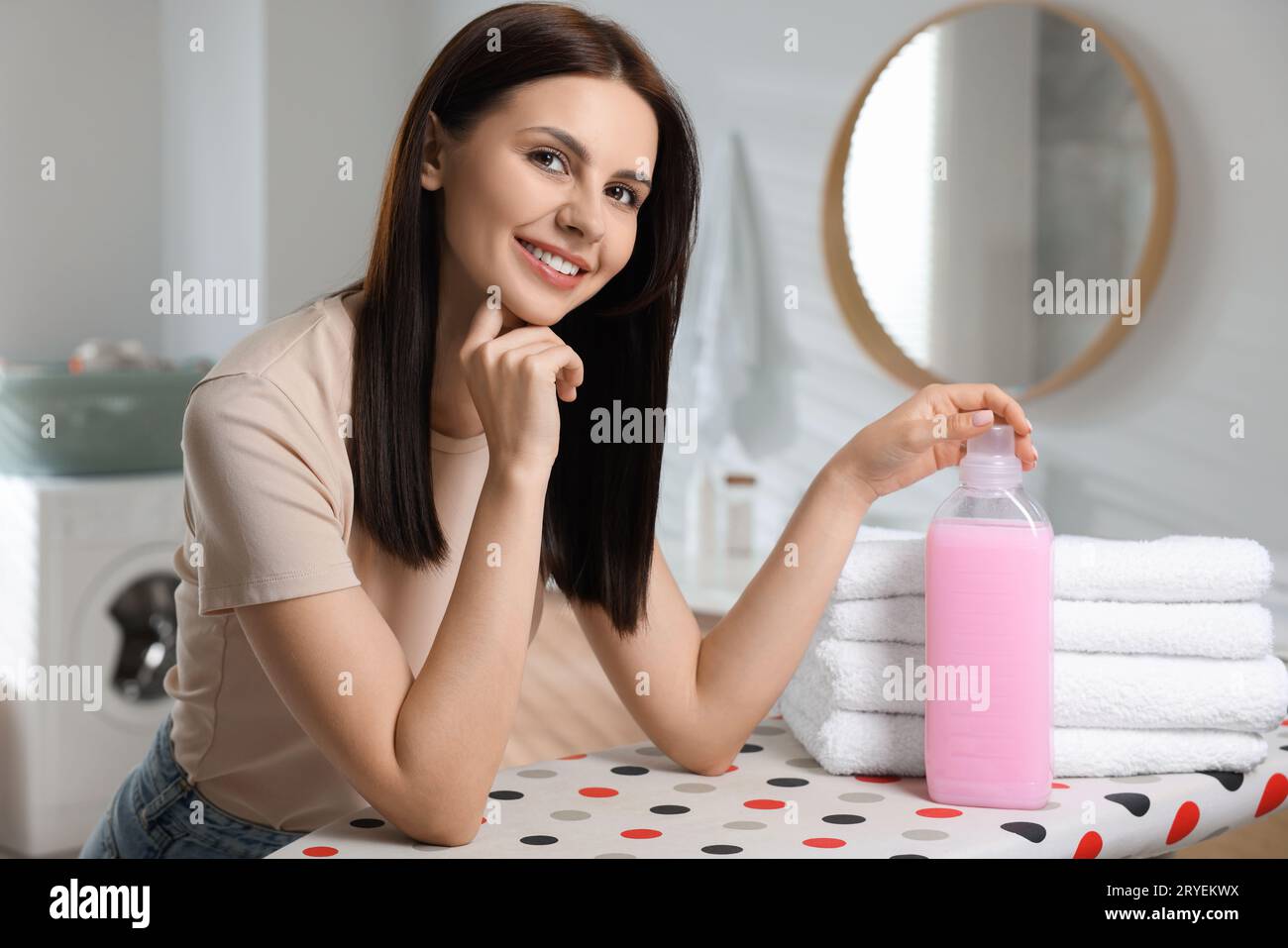Woman near clean towels and fabric softener in bathroom Stock Photo Alamy