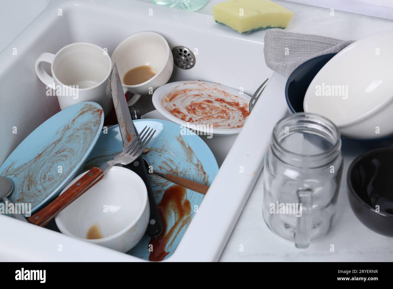 Sink with many dirty utensils and dishware in messy kitchen Stock Photo
