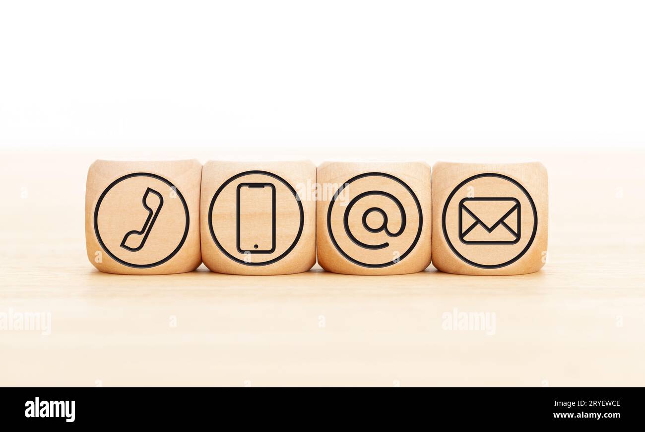 Contact us icons in wooden blocks on wooden desk. Copy space Stock Photo