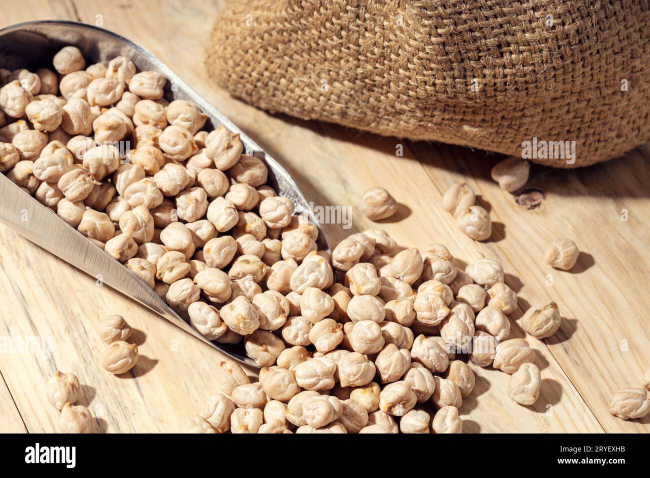 Uncooked Chickpeas on scoop on rustic wooden table. Rustic still life Stock Photo