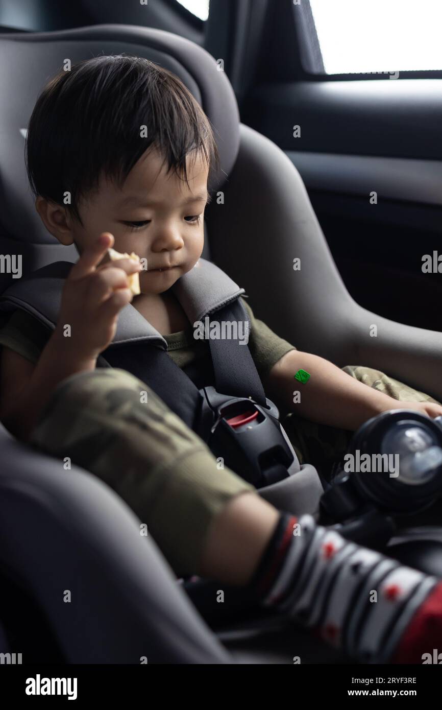Happy Asian Chinese age 1 2 years old kid enjoying his food while sitting on safety car seat Stock Photo Alamy