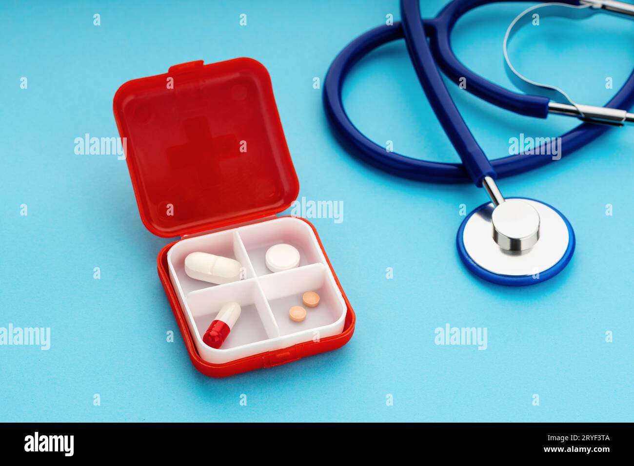 Daily Pill box and stethoscope on blue background. Medicine, healthcare