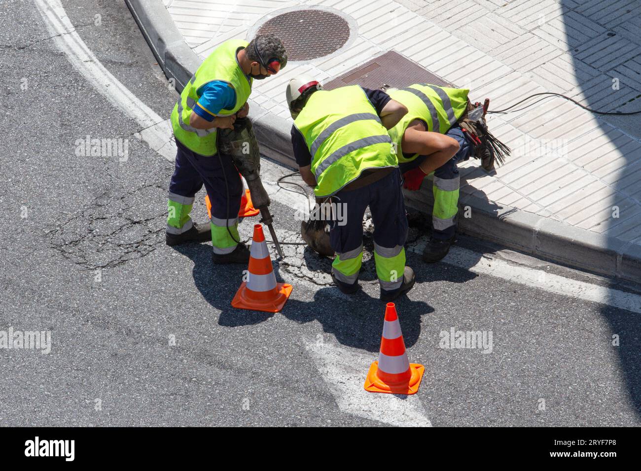 Group of construction Workers repairing an asphalt road on city. Paving maintenance Stock Photo
