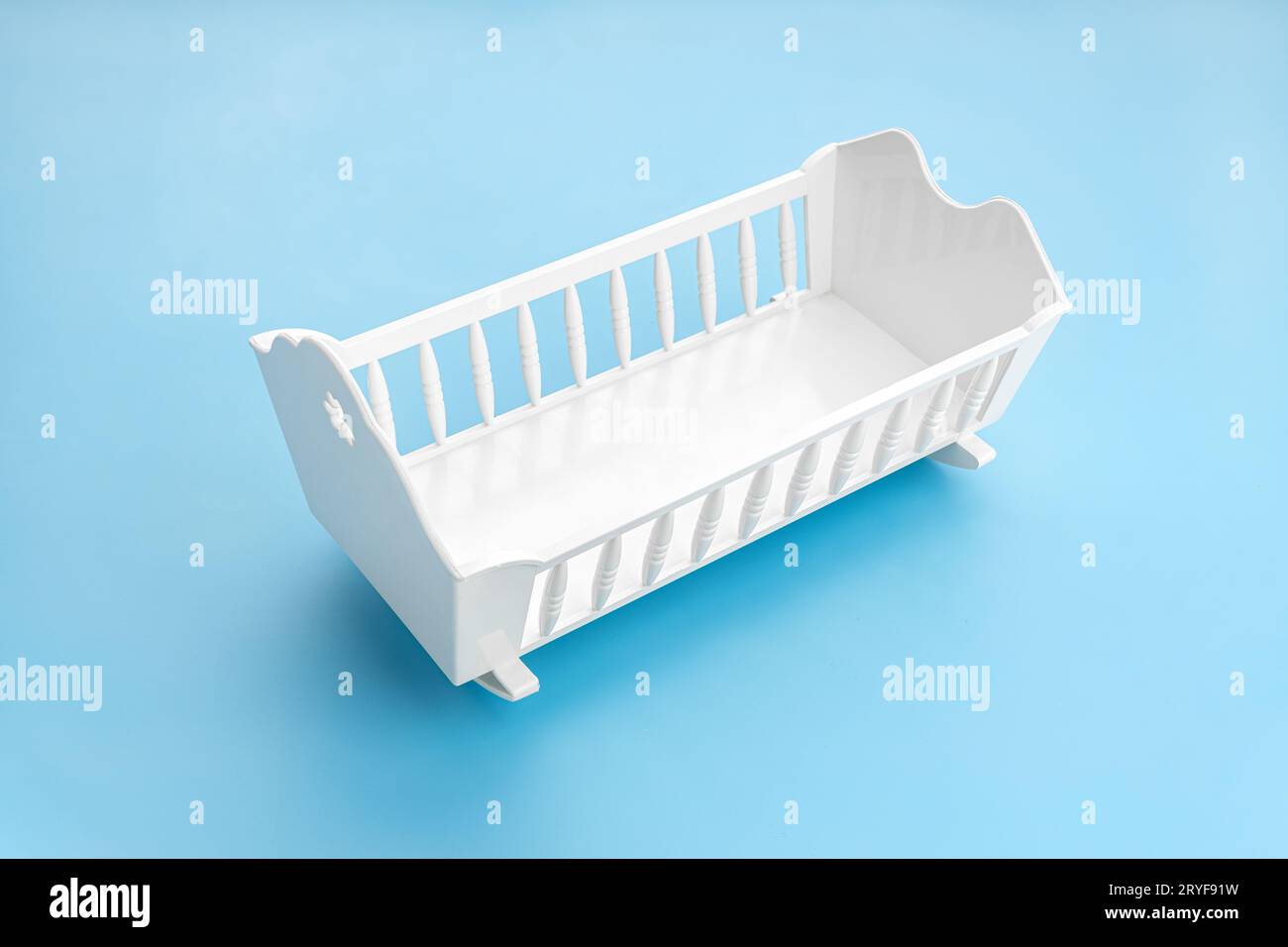 White baby crib isolated on blue background. Child birth rate concept