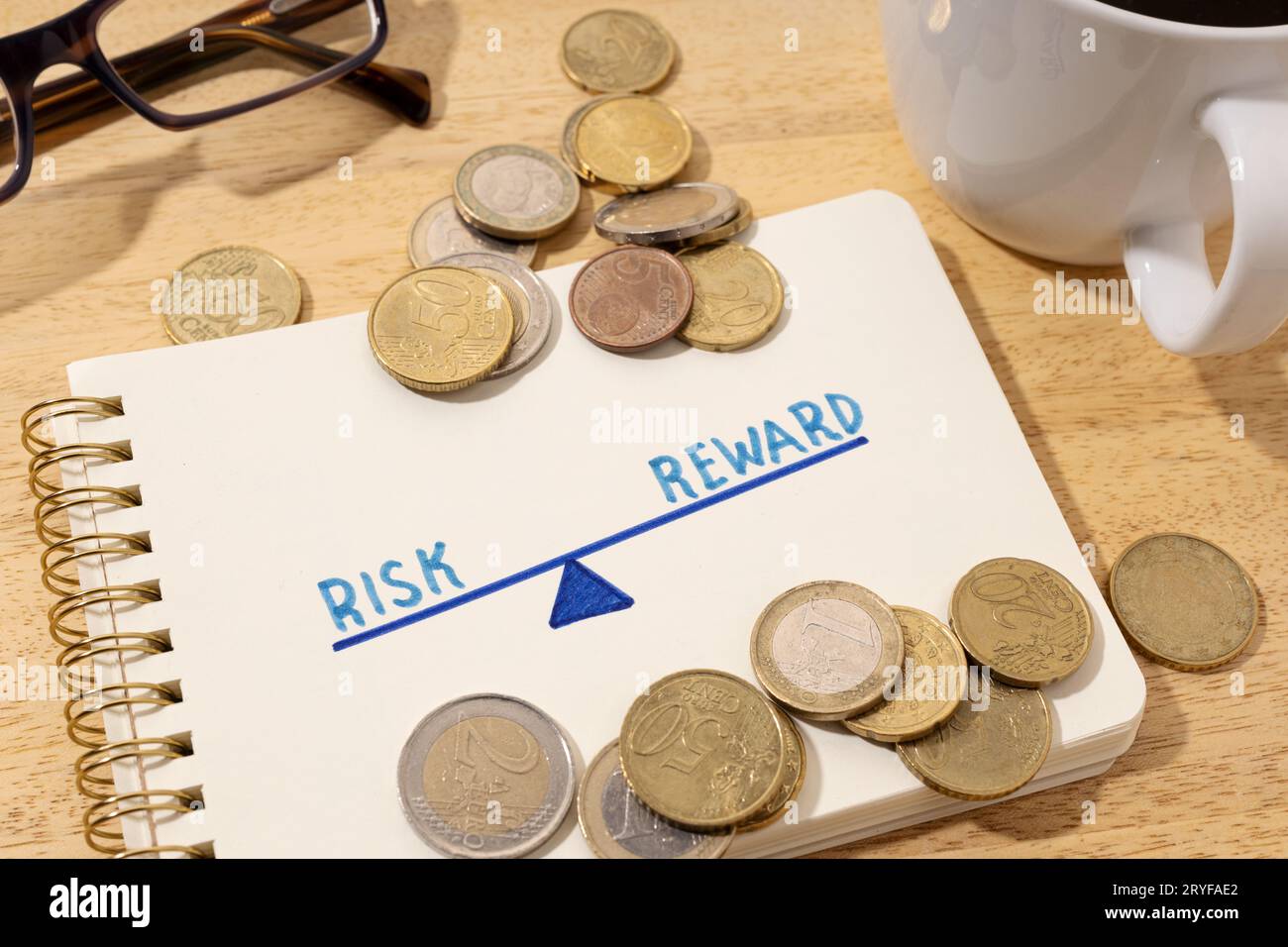 Risk reward concept. Drawing on notepad and coins on desk Stock Photo ...
