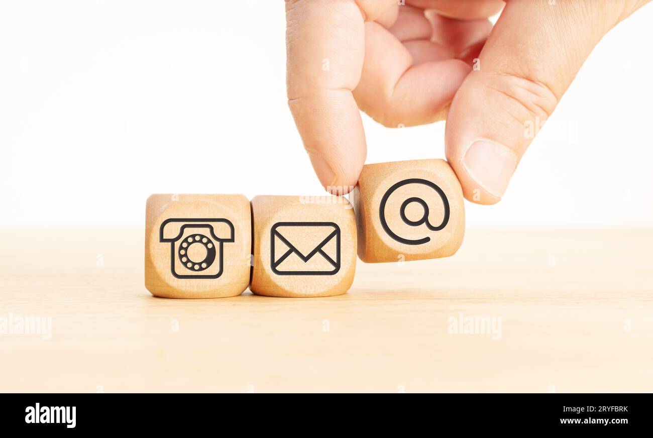 Contact us icons on wooden blocks. Hand holding a dice with communication icon. Copy space Stock Photo