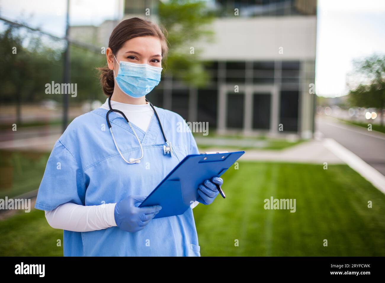 Modern female medical doctor standing on the lawn outside hospital facility Stock Photo