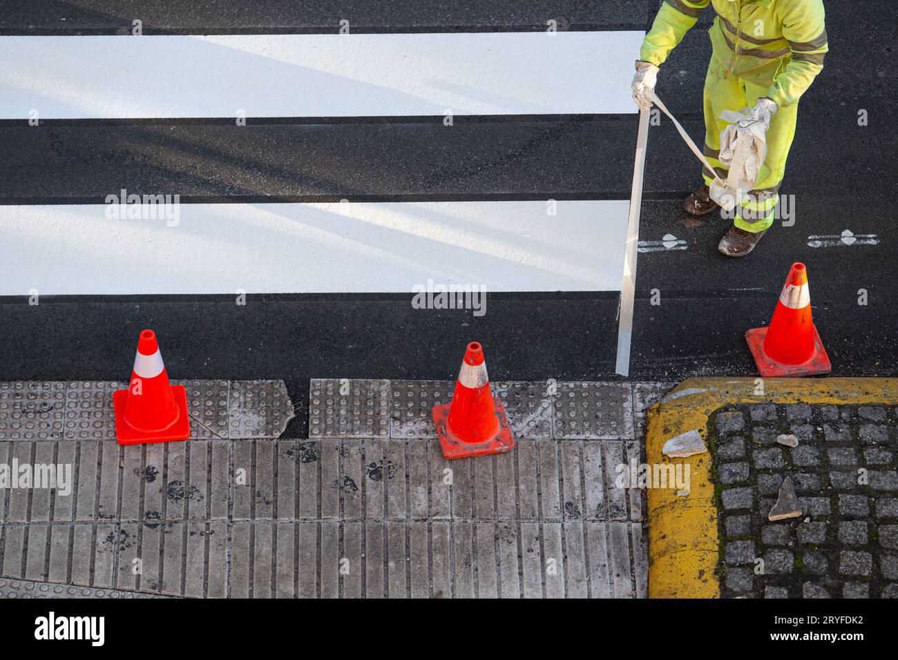 Worker removing masking tape after painting a zebra crossing on a city