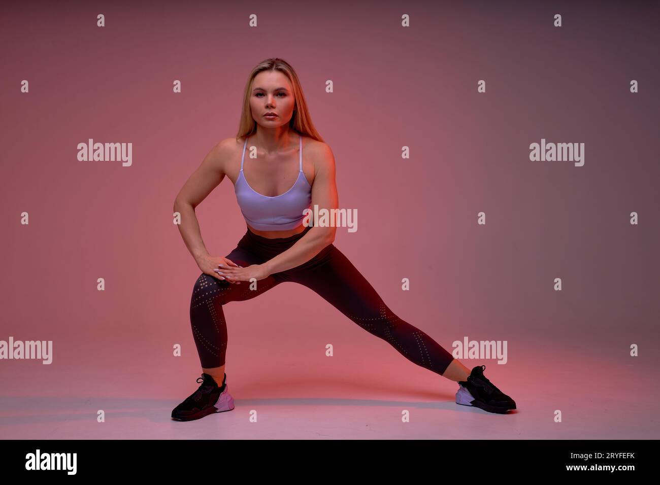 Full-length photo of sporty motivated ambitious fair-haired woman doing side lunge exercises isolated over purple background, health and body care, we Stock Photo