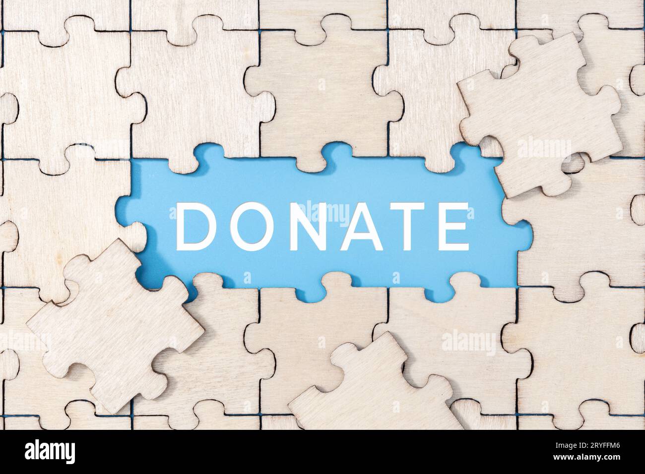 Donate word on blue background surrounded by puzzle pieces Stock Photo