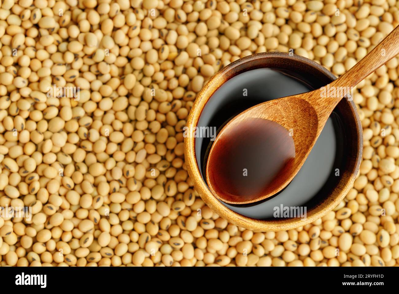 top view of soy sauce in bowl and in spoon on dry soybeans as background Stock Photo