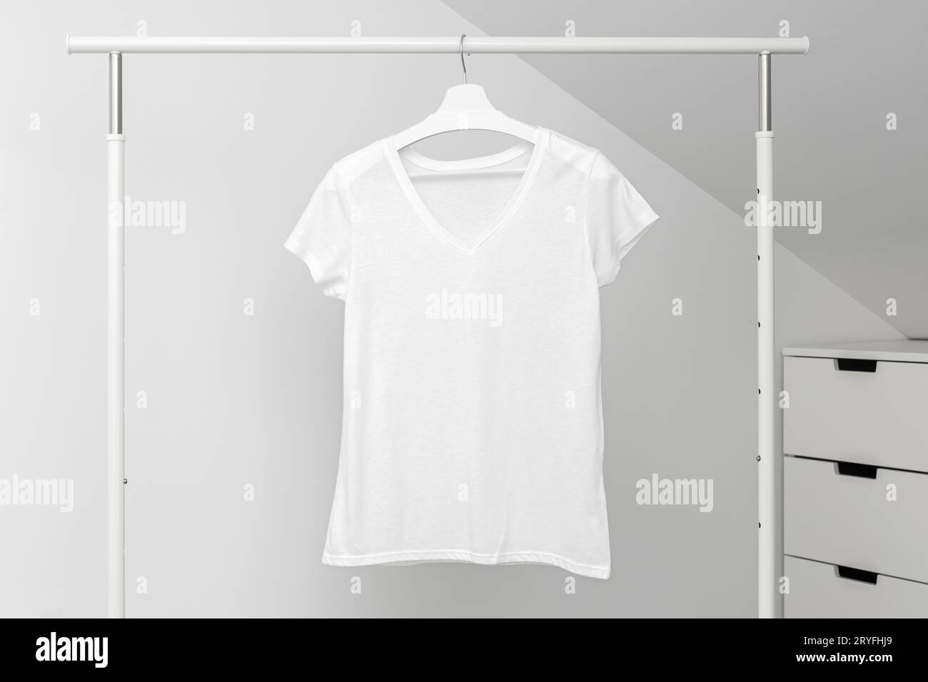 Group of Assorted t-shirts hanging on white hangers. Clothing rack Stock Photo