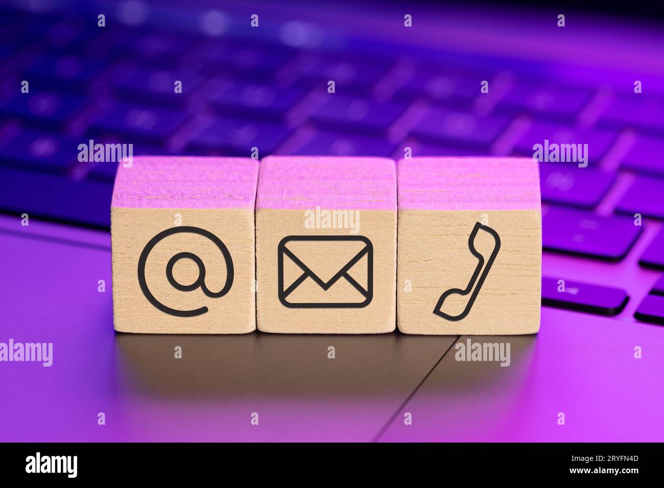 Contact us icons on wooden blocks on laptop with colorful lights Stock Photo
