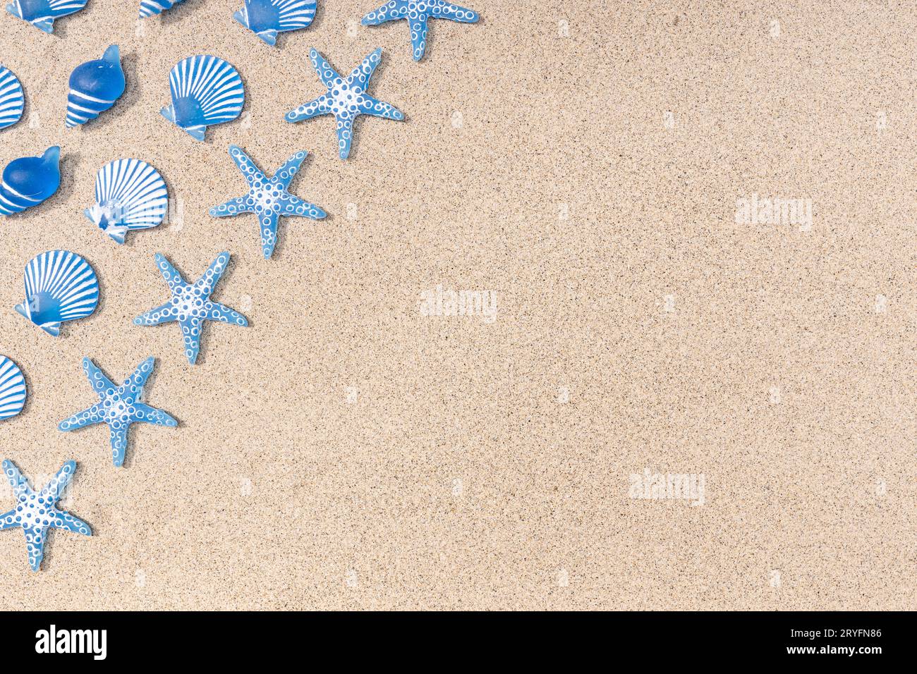 Summer background with blue seashell pattern on beach sand background. Copy space. Top view Stock Photo