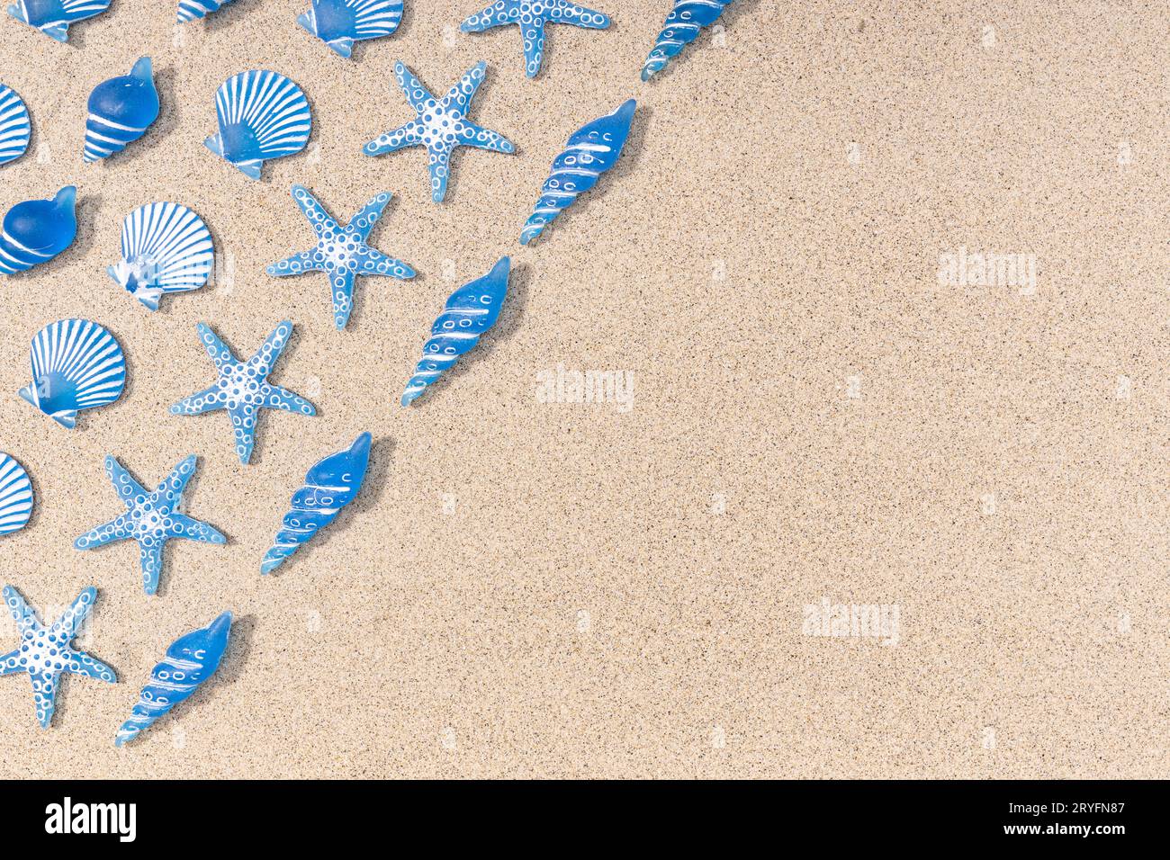 Summer background with blue seashell pattern on beach sand background. Copy space. Top view Stock Photo