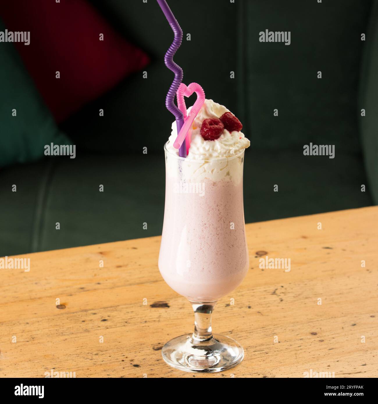 Closeup shot of a healthy strawberry smoothie in a mug with drinking tubules on a wooden table Stock Photo