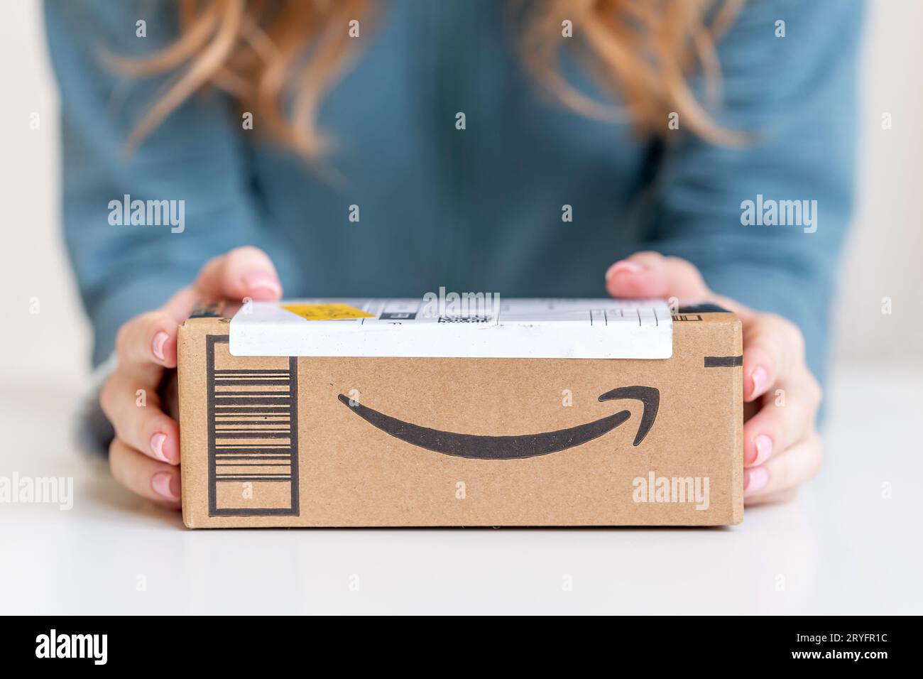 Woman holding in hands cardboard box delivered from Amazon Stock Photo