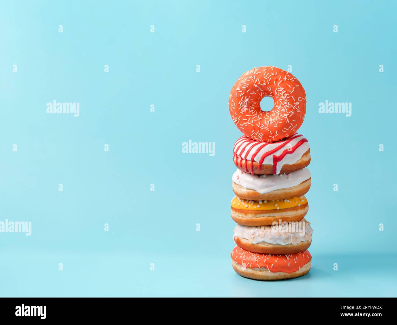Stack of donuts on blue background with copy space Stock Photo