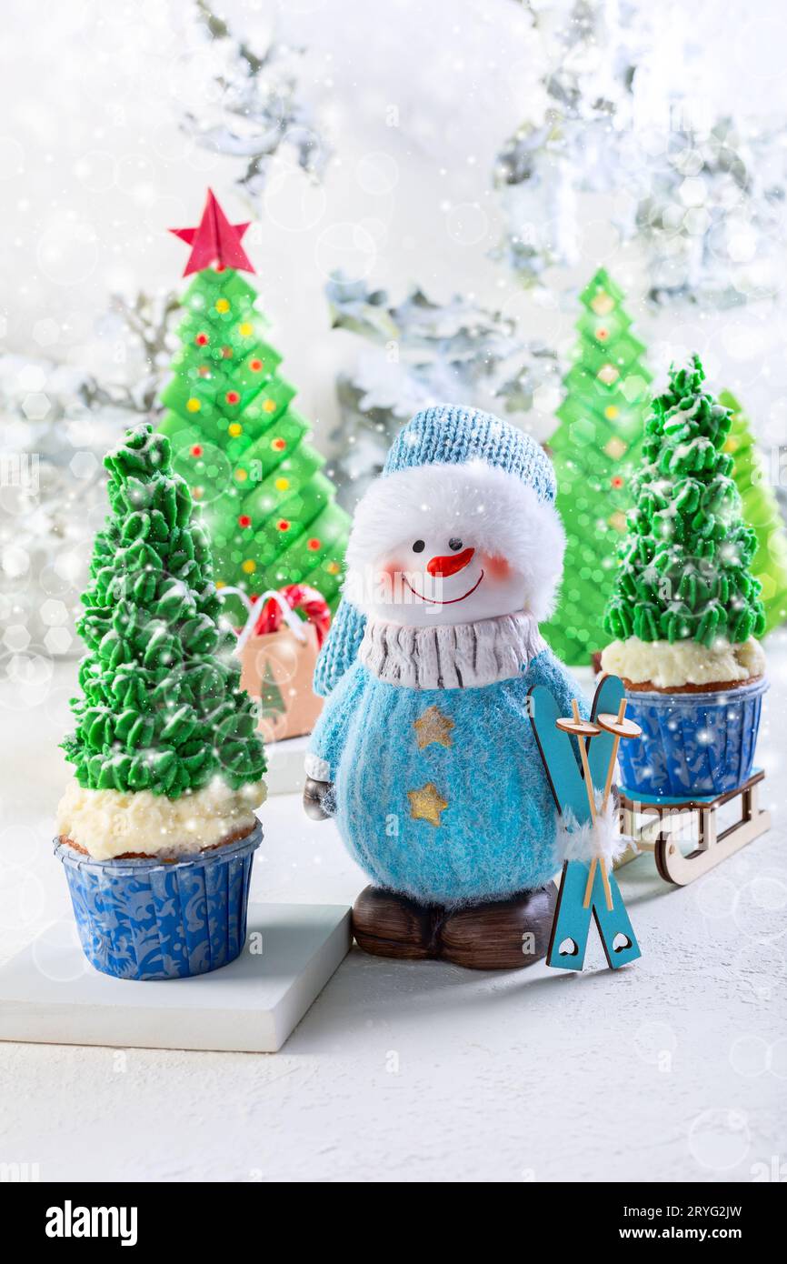 Card with a snowman and cupcakes in the form of Christmas trees. Stock Photo