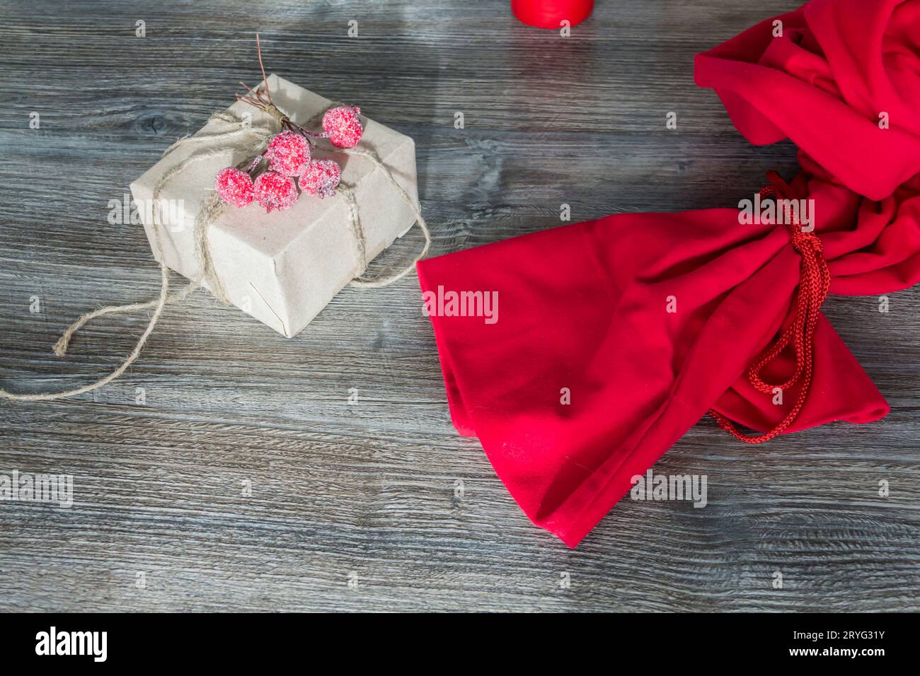 Red Santa Claus bag and gift packed in craft packaging on a wooden surface background. Preparation for the holiday. Stock Photo