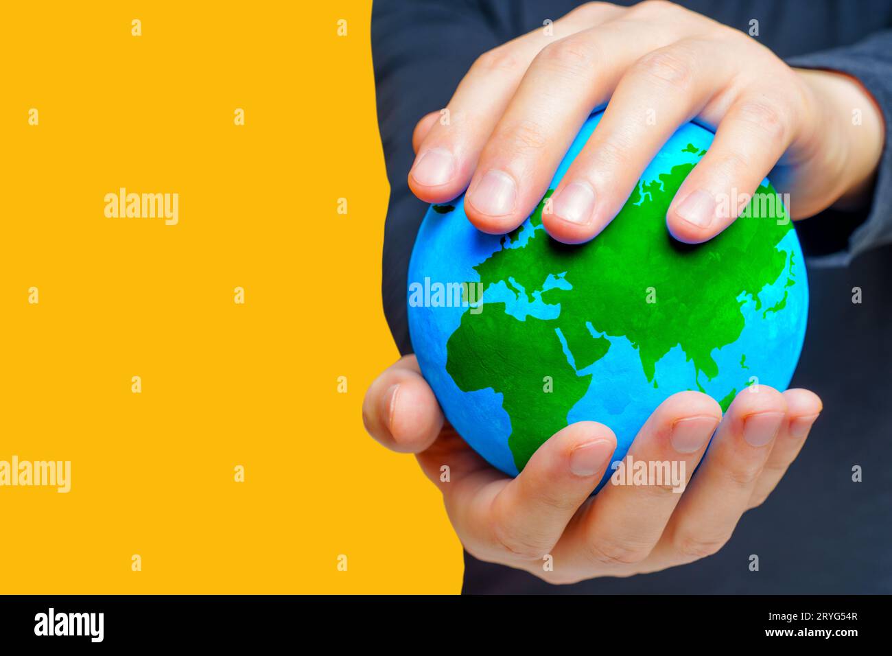 Man cradling a globe adorned with lush green continents against a clean ...