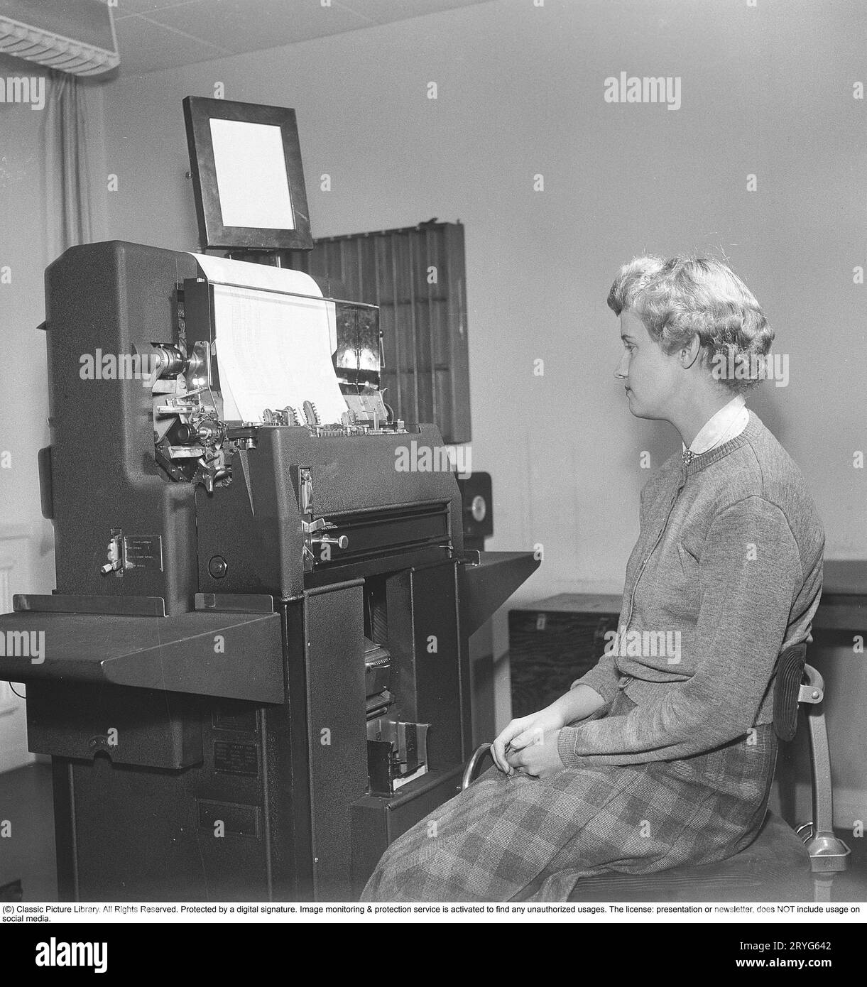 In the 1950s. A female clerk at punch card reader machine overlooking it's function and the feed of  the punch cards into the machine. Punched cards was created by another machine, entering information, creating the punch cards as a storage medium where the punched holes in the paper card were the input information. The picture shows the machine reading the information from the punch cards, then printing it. The machine is made by the british manufacturer Powers-Samas who developed the encryption machine, far better and safer then the german Enigma.  Sweden 1954. Kristoffersson ref BM85-10 Stock Photo