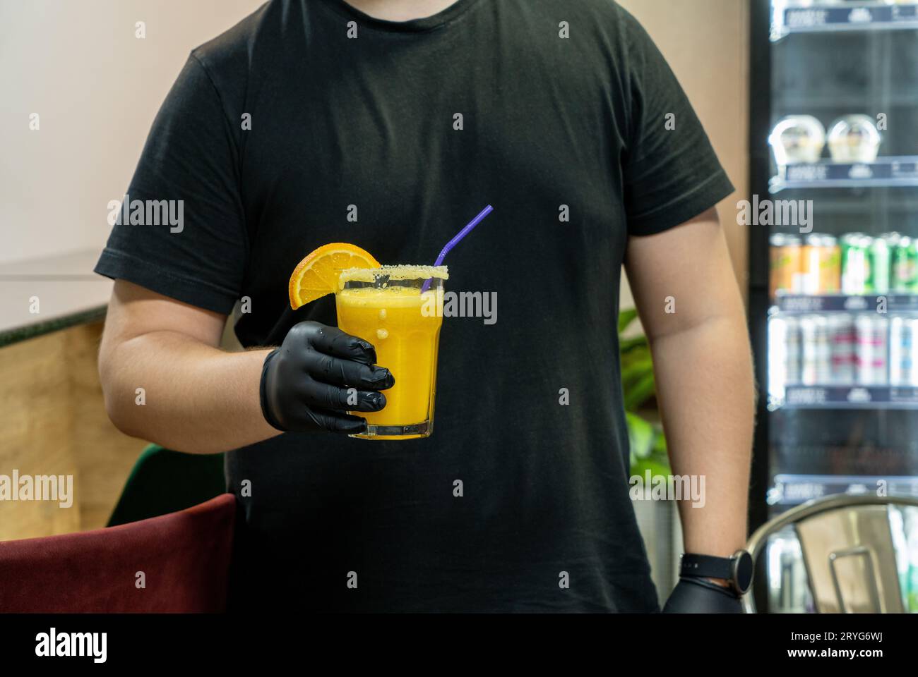 A closeup of the bartender holding a glass of orange drink in sports complex Stock Photo