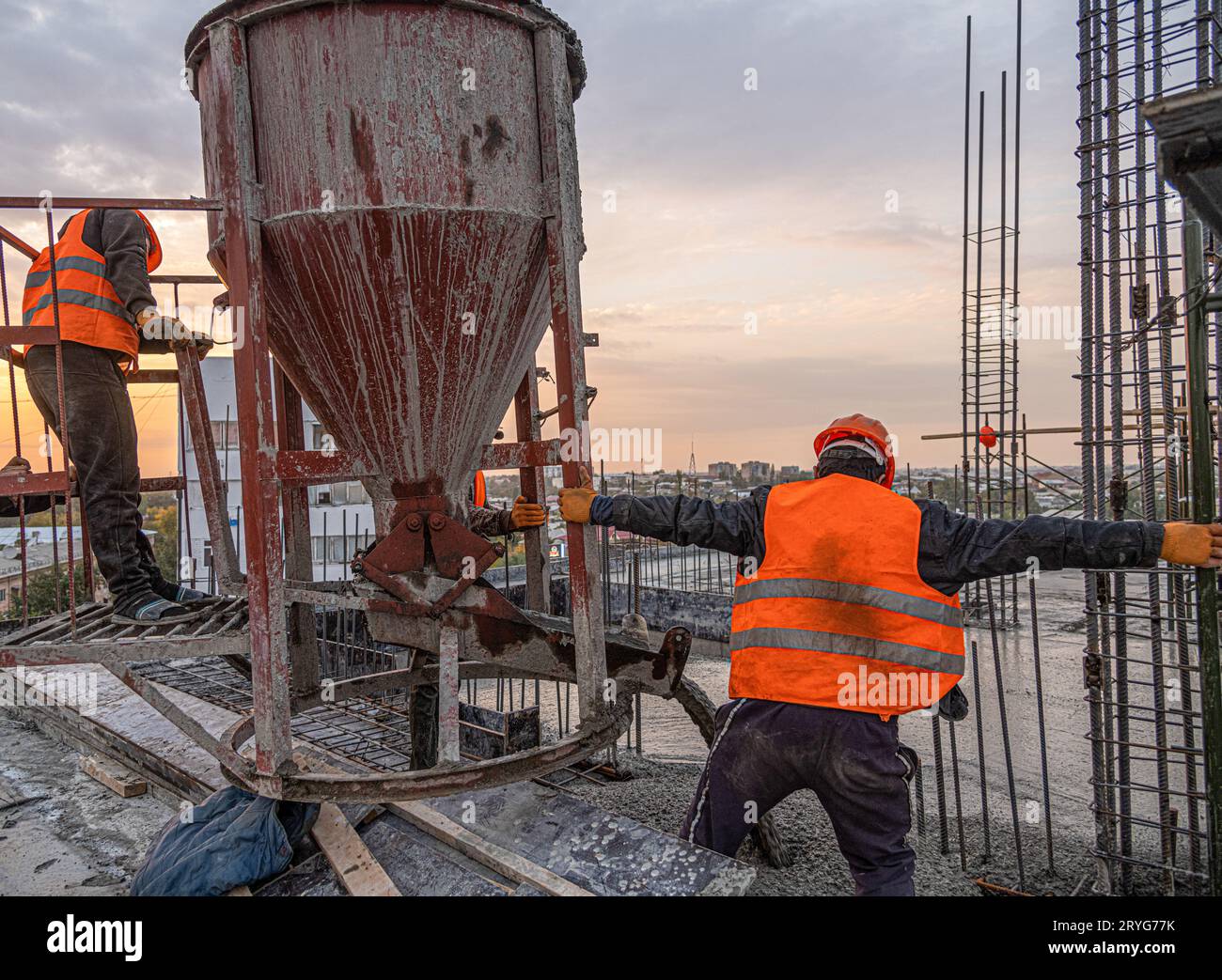 The workers on a building infrastructure roof with machinery and tools. Pouring concrete into a