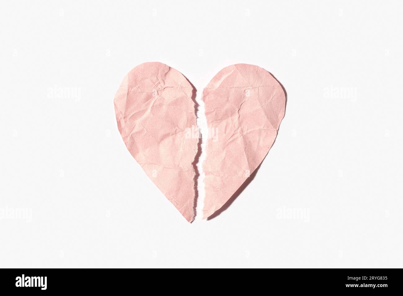 Broken heart made of pink crumpled paper isolated on white background Stock Photo