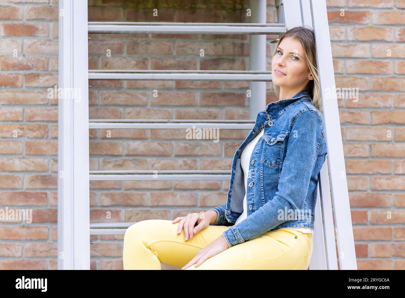 https://c8.alamy.com/comp/2RYGC6A/stylish-brunette-girl-wearing-jeans-vest-white-t-shirt-and-yellow-jeans-posing-against-stairs-in-the-city-urban-clothing-styl-2RYGC6A.jpg
