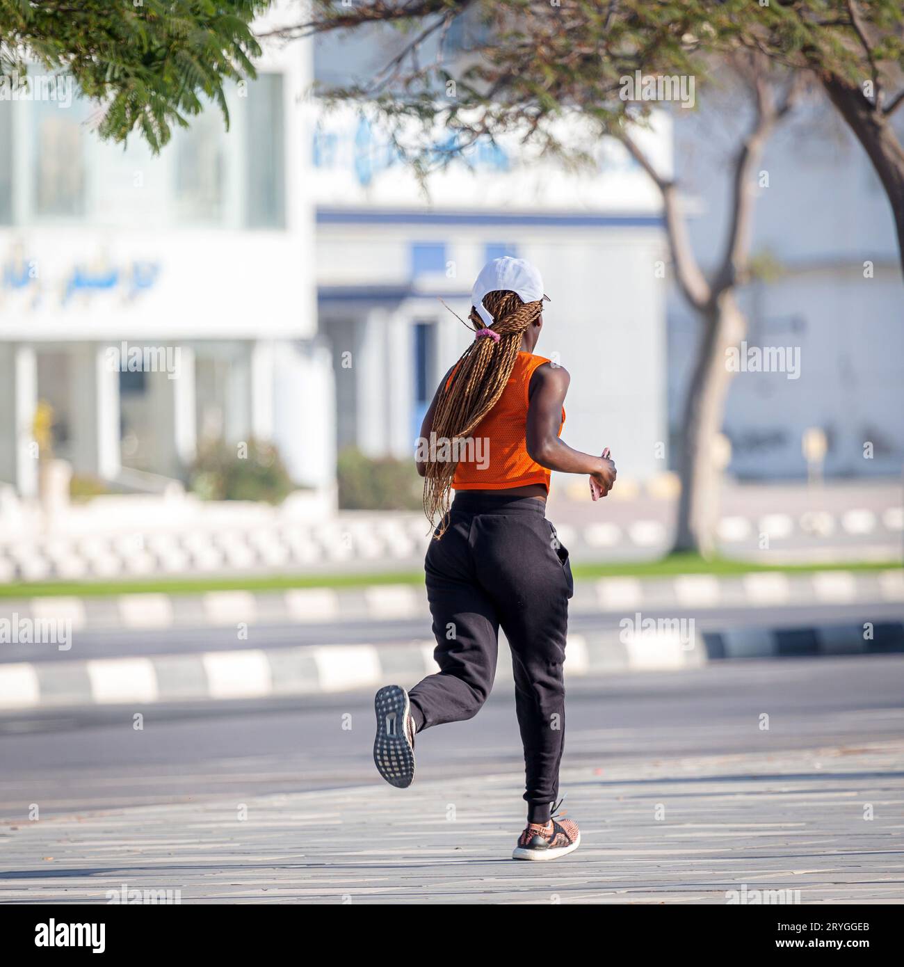 Ras Al Khaimah, UAE - February 5, 2022: African-american woman running on the street, active lifestyle Stock Photo